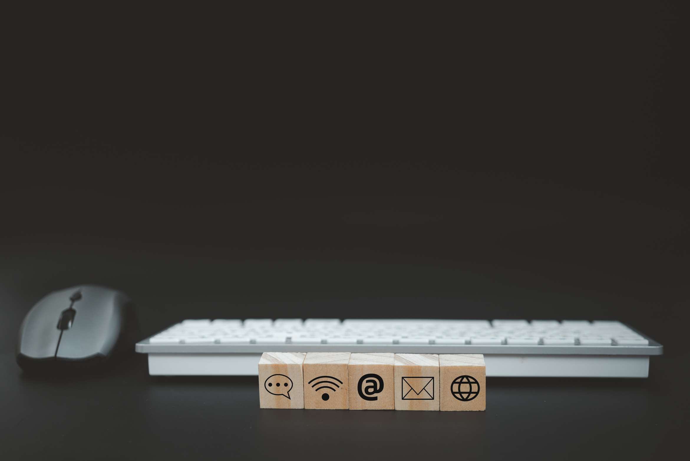 Online business communication symbols contact us or e-mail address marketing concept on wooden cubes with computer keyboard background.